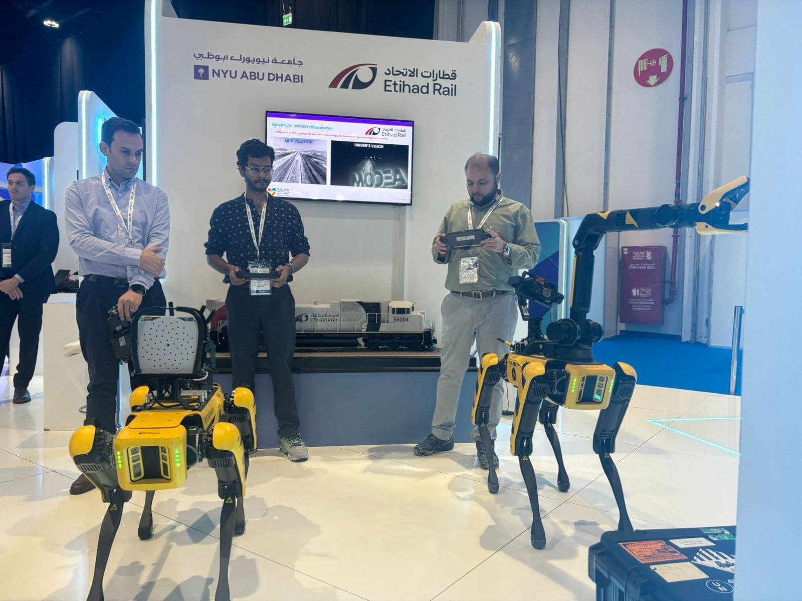 Three Spot quadruped robots and the NYUAD team presenting rail robotics at the Etihad Rail booth