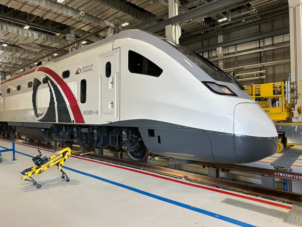 Spot beside an Etihad Rail locomotive inside the depot hangar, collecting multimodal inspection data for predictive maintenance