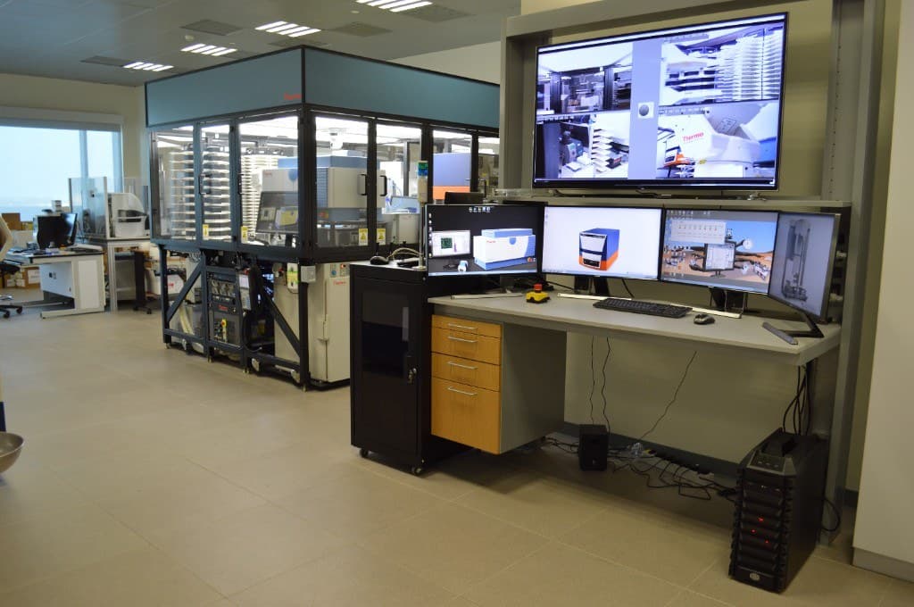 Wide view of the HTS robotic enclosure beside the multi-monitor operator control station