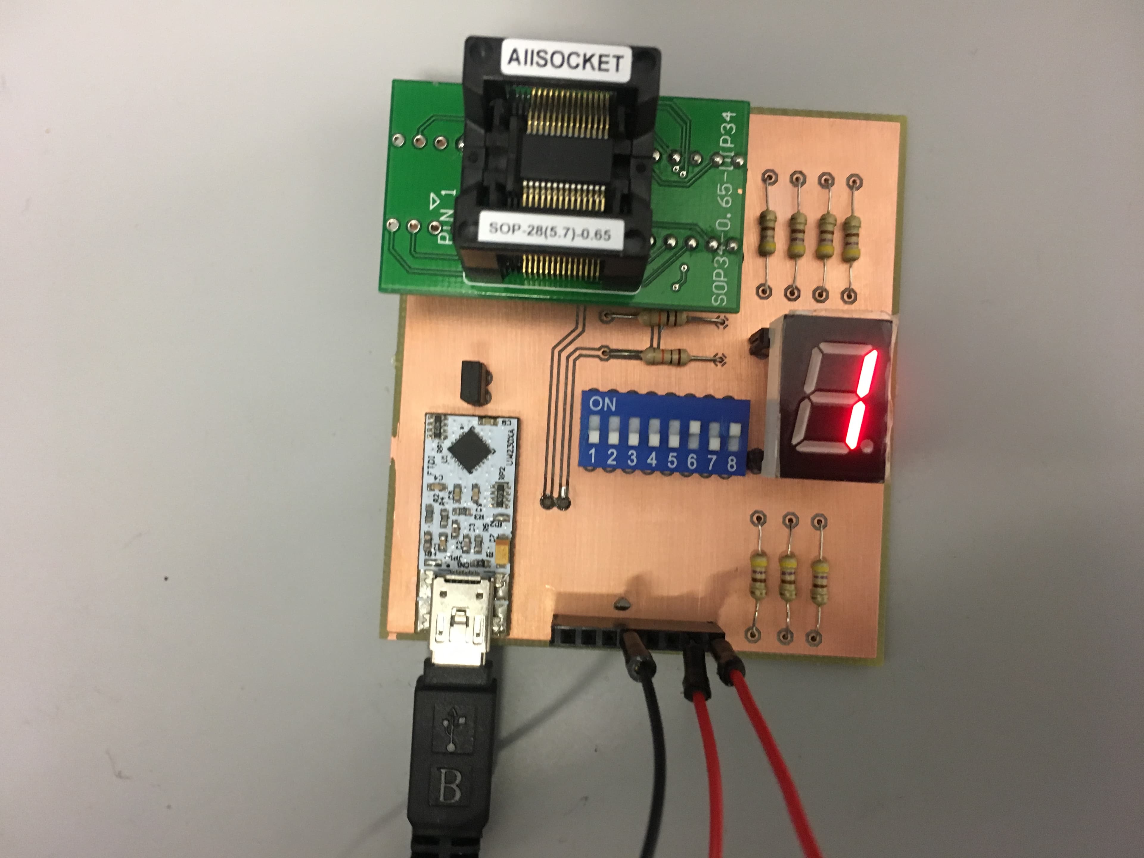 Close-up of the populated chip-test PCB showing the SOP-28 test socket, DIP switch block, and illuminated seven-segment display